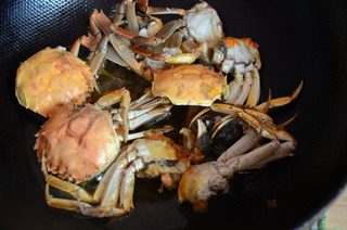避风塘炒蟹,翻炒至蟹脚变红,捞出螃蟹沥油。