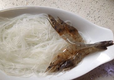 蒜蓉粉丝开片虾 ,一小把白粉丝用温水泡软,沥干铺于盘中,将虾展开铺于粉丝上,如图示;