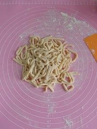 蔓越莓沙琪玛,将擀好的面饼切成6cm长的面条,切好的面条撒一些生面粉避免粘连。另一份面团也是如此处理。