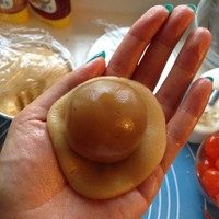 广式蛋黄莲蓉月饼,一边手用手指轻轻摁住蛋黄,另一只手从下往上把莲蓉推上来