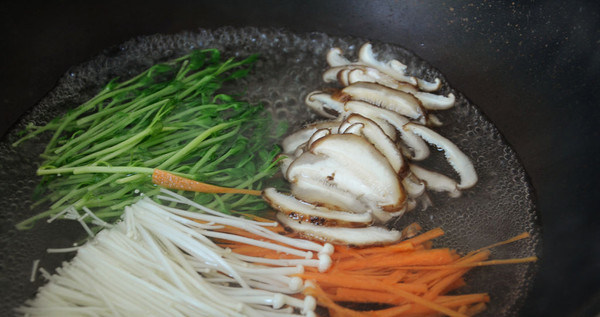 石锅拌饭,锅内烧开水,放入金针菇,,豆苗,香菇,胡萝卜丝烫1分钟,喜欢更熟一点的可以烫久一些
