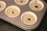 三重黑芝麻杯子蛋糕,将夹心挤入(放入)蛋糕体糊中,表面用蛋糕糊轻轻覆盖。