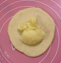面包超人,松弛后的60克的面团擀成圆形,翻面后包入馅料并封好口,收口朝下放入烤盘中并压扁。