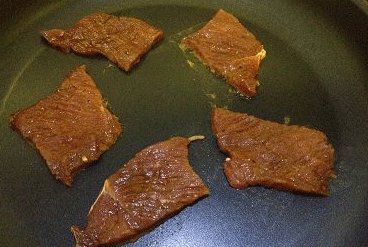 香辣手撕牛肉干,平底不粘锅不放油，将牛肉一片片拎出(去除调味料)，平铺于锅中；