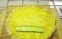 三色蛋卷,将寿司帘平放(如果没有就不用),将一张蛋饼放在上面,放上一些黄瓜片。