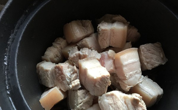 梅干菜烧肉,肉块放在梅干菜上,然后加入开水,没过肉块