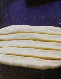 椰蓉面包,将松弛好的面团擀成圆形，翻面后放入椰蓉馅料，收紧口，将面团擀成长长的椭圆形，用利刀在上面化上4刀。