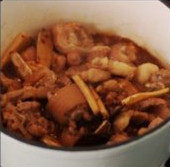 酱香焖猪尾,开火,加入炸香的蒜头,大火收汁,加入大量的葱段