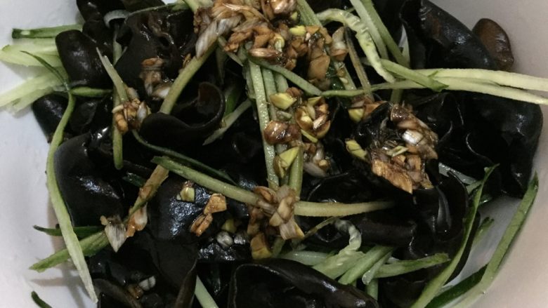 凉拌芥末木耳,如图焯熟沥干水分的木耳倒入容器中,加入黄瓜丝,淋入调好的汁,搅拌均匀
