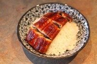 蒲烧鳗鱼饭,将微波炉叮好的鳗鱼切段,铺在米饭上