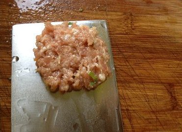 翡翠蒸豆腐,用小勺取肉馅放在菜刀上,压成豆腐的大小,薄薄一层即可;
