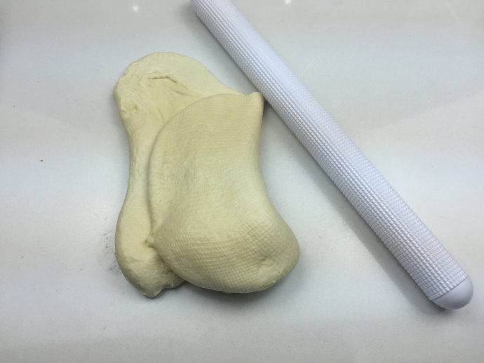 蜜豆小面包,将发酵好的面团取出,用擀面杖擀压排气