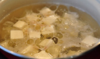 芥菜豆腐蛤蜊汤,锅里加入<a style='color:red;display:inline-block;' href='/shicai/ 845'>高汤</a>和姜丝煮滚，煮滚的<a style='color:red;display:inline-block;' href='/shicai/ 845'>高汤</a>里放入豆腐块儿，再次煮滚（酌情滴入少量油，主要是为了保持待会儿煮的青菜的美丽色泽）；