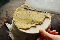 手制地瓜干,找一个饼干罐头，底部带一个浅浅的凹面的（浅一点的好，地瓜泥可以铺的薄）。底部凹面铺上沾湿的纱布（沾湿防粘）。舀上地瓜泥，用菜刀刮平，来回多刮压几下，让结构更密实。