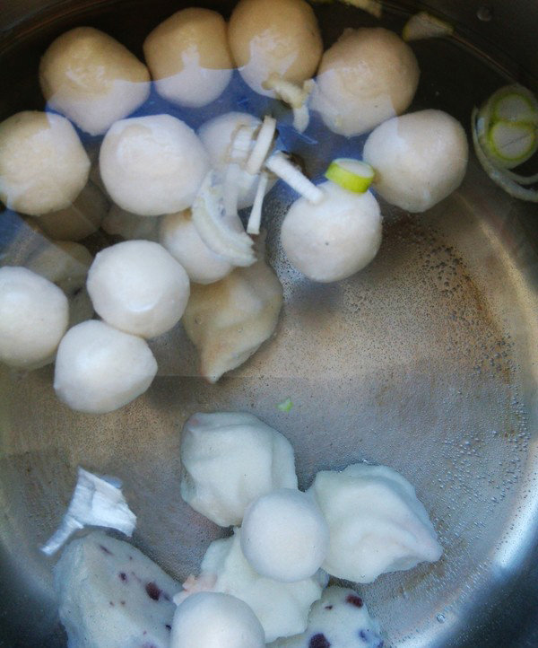 家常菠菜鱼丸汤,锅中放适量水,将未解冻的鱼丸,葱花直接放入水中加热