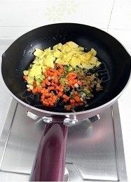 金枪鱼什锦炒饭,将炒好的鸡蛋拨到锅子的一边,放入葱花、榨菜和胡萝卜丁翻炒至葱花和榨菜出香味