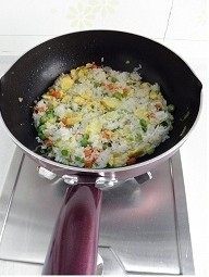 金枪鱼什锦炒饭,用铲子将结块的米饭弄散,将米饭同锅中的菜料炒匀
