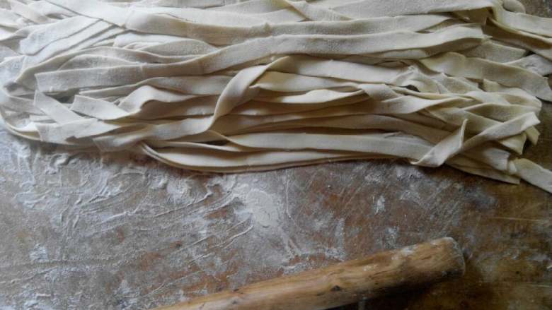 手擀面,把面团擀成一张大薄饼状，稍作叠加后切成条，切的过程中多加<a style='color:red;display:inline-block;' href='/shicai/ 519'>面粉</a>，以免粘在一起，然后抖开