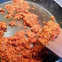 马来西亚辣椒板面,锅中热油,倒入绞碎的材料翻炒,由大火转中火(怕糊可以转小火)。炒至辣椒变干,颜色变深,但一定不能糊。这个过程可能需要30分钟左右。