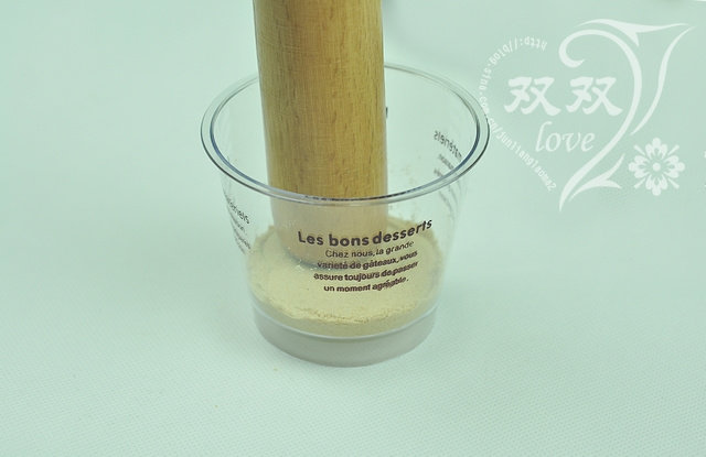 木糠杯,舀少许饼干碎放入杯中,用勺背或者擀面杖等硬物压实