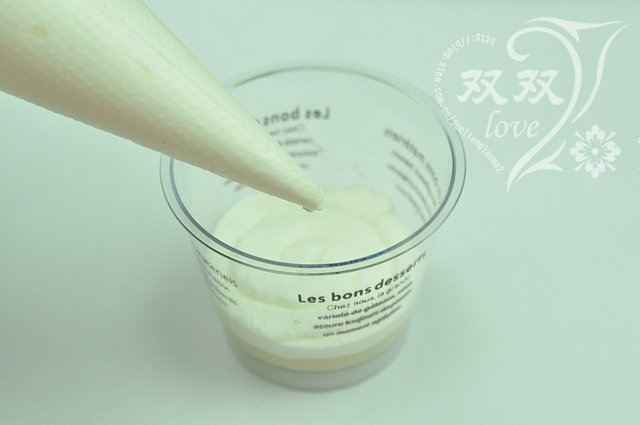 木糠杯,裱花袋剪开个小口,将奶油一圈一圈挤在饼干碎上