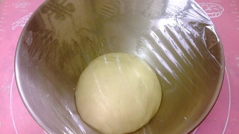 椰香奶酥辫子面包,揉好的面团滚圆,放入厨师机,盖上保鲜膜,进行一次发酵。