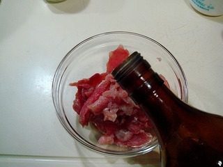腐乳爆肉,浆制肉片,先撒入少许味精和盐,倒入少许绍酒。