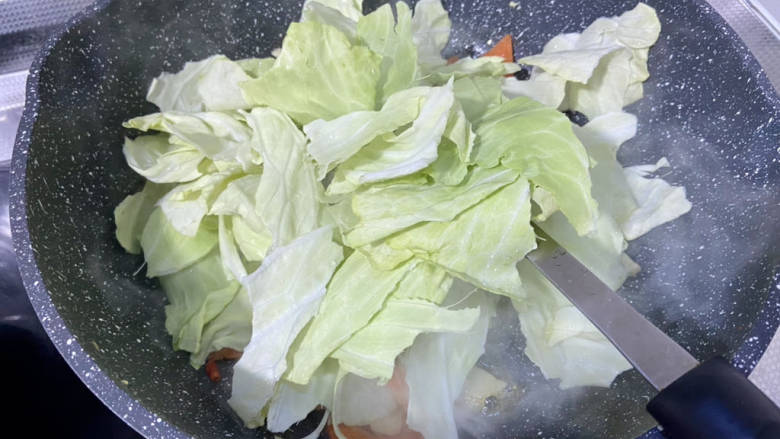 包菜胡萝卜炒鸡蛋,加入包菜叶,中大火,翻炒两分钟,可以中火炕半分钟,让包菜边缘微焦,会更香