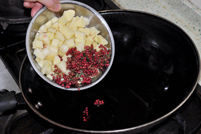 牵手知秋,锅内菜油五成油温时下入仔姜块、鲜花椒、红椒节炒香
