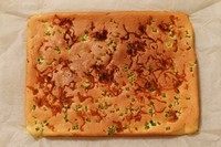 香葱肉松蛋糕卷,表面上色程度如图,用手轻拍蛋糕表皮不粘手也不硬就是烤好了。取出烤好的蛋糕,撕开四周的油纸。