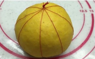 黄金南瓜豆沙面包,逐个把每个面团都系好后,依次放入烤盘,中间隔开距离,放到烤箱里面,烤盘下方放盘热水,进行二次发酵。