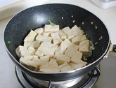 家常烧豆腐,放沥水后的豆腐,小心的晃动锅子,让豆腐均匀的沾到花生油方便定型。