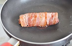 培根鸡肉卷,烤好取出放入平底锅中,中小火煎至表面焦黄,取出切开装盘配蔬菜色拉食用。