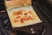 肉松奶酪厚蛋烧,在蛋液上层还没有完全凝固的时候就卷起来推到锅的上方,然后再倒入剩下的一半蛋液,加料。