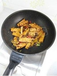 芹菜豆干炒鱿鱼须,翻炒至豆干表面微焦。注意:豆干不容易入味,所以最先放入