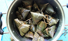 香菇红烧肉粽子,用草绳把粽子绕两圈绑起,然后用剪刀剪去多余的粽叶即可。全部粽子绑好后,入锅,加入抹过粽子的水,大火烧开后小火熬2个小时,或者可以放入压力锅按“蹄筋”键煮好,可以缩短时间