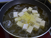 椒盐炸豆腐,将豆腐一块一块入锅,并用漏勺轻轻搅动以免粘锅或相互粘连,