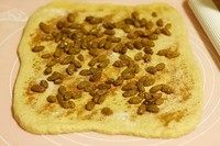 肉桂葡萄干面包 ,酒渍葡萄干控干酒备用。当听到机器发出响声,把面团拿出来,擀开撒上一层肉桂粉,一层细砂糖,铺上葡萄干,卷起来,切成四段。
