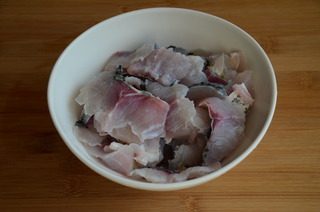 酸菜鱼,将剔完鱼骨的鱼段鱼皮朝下,从尾部开始,斜刀片成鱼片
