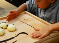 巧虎牛奶小馒头,将巧克力面团分成几份，案板撒干粉，两手不断搓成细长的条状，分别做巧虎的眉毛，额头的王字，嘴巴。