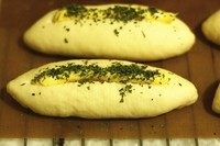 蒜香餐包,面团发酵好后,在表面划出一条口子,挤上蒜蓉黄油,撒些欧芹