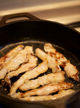 猪颈肉盖饭,将猪颈肉放入锅内,煎至边缘卷起并有焦糖色时翻面,将火减小至中火,取出煎好的猪颈肉待用,此时锅底应有焦糖色物质粘着