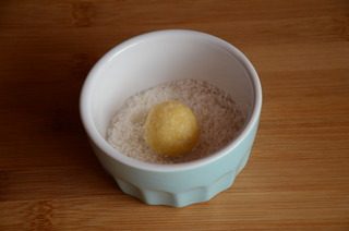 黄金椰丝球,取一小块面团,搓成小球,在椰丝碗里滚一圈,表面均匀沾上椰丝