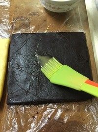 马赛克饼干,取出两个冻好的面团,用剪刀分别剪开两个保鲜袋的一面。在其中一个面团上,涂刷一层蛋液(分量外)。保鲜袋不要扔掉,整形的时候借助它不粘手,不散形,很有用。