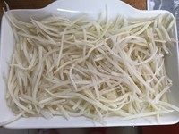 香薰培根香肠土豆羹,土豆擦丝铺在考碗里
土豆丝不要准备太多，不容易熟。记得选用宽一点的烤盘，这样铺的面积大容易熟。如果是比较深的烤碗，可以提前在微波炉里转一下，让土豆丝稍微半熟~