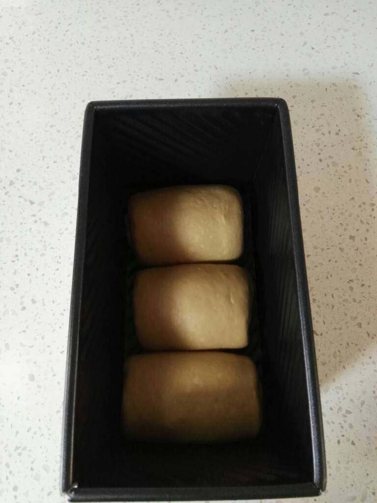 奶咖糯米粉吐司,再次擀开成椭圆形,卷起2.5~3个圈,收口向下,排入吐司模。