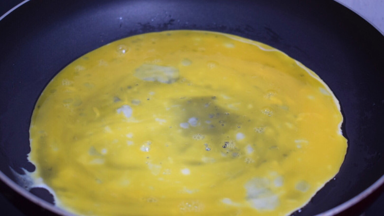 秋葵煎蛋,平底不粘锅刷一层薄薄的食用油后开小火,倒入1/3的蛋液轻轻转动锅子,使蛋液铺满锅底