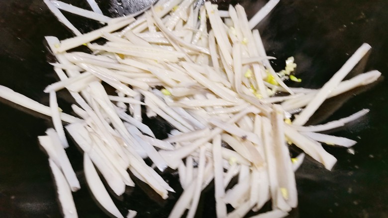 酸辣藕丝,起锅烧油,下入姜蒜,再把莲藕丝放入