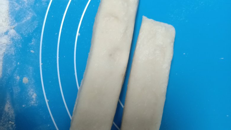 豆角焖卷子,将一块大面团切成两半,再将两半叠在一起,从中间拉伸,手捏着两边分别以相反方向卷起