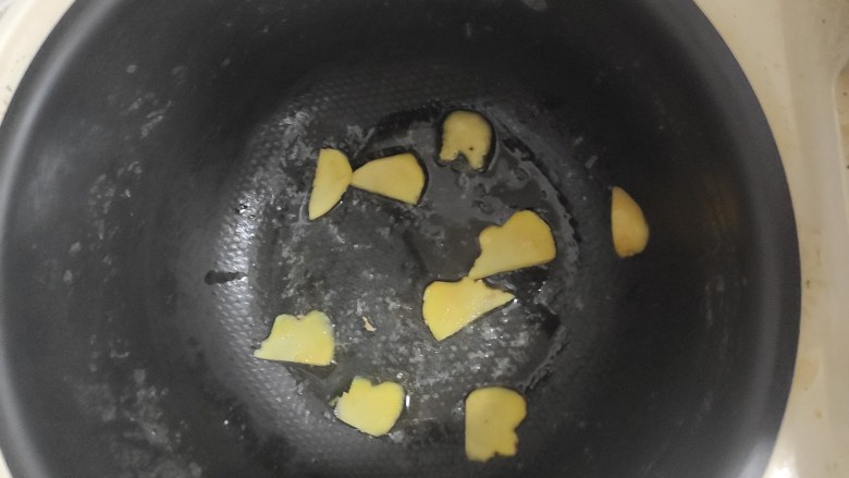 蜜汁五花肉,电饭锅预热3-5分钟后,放入油跟姜片煮2分钟。